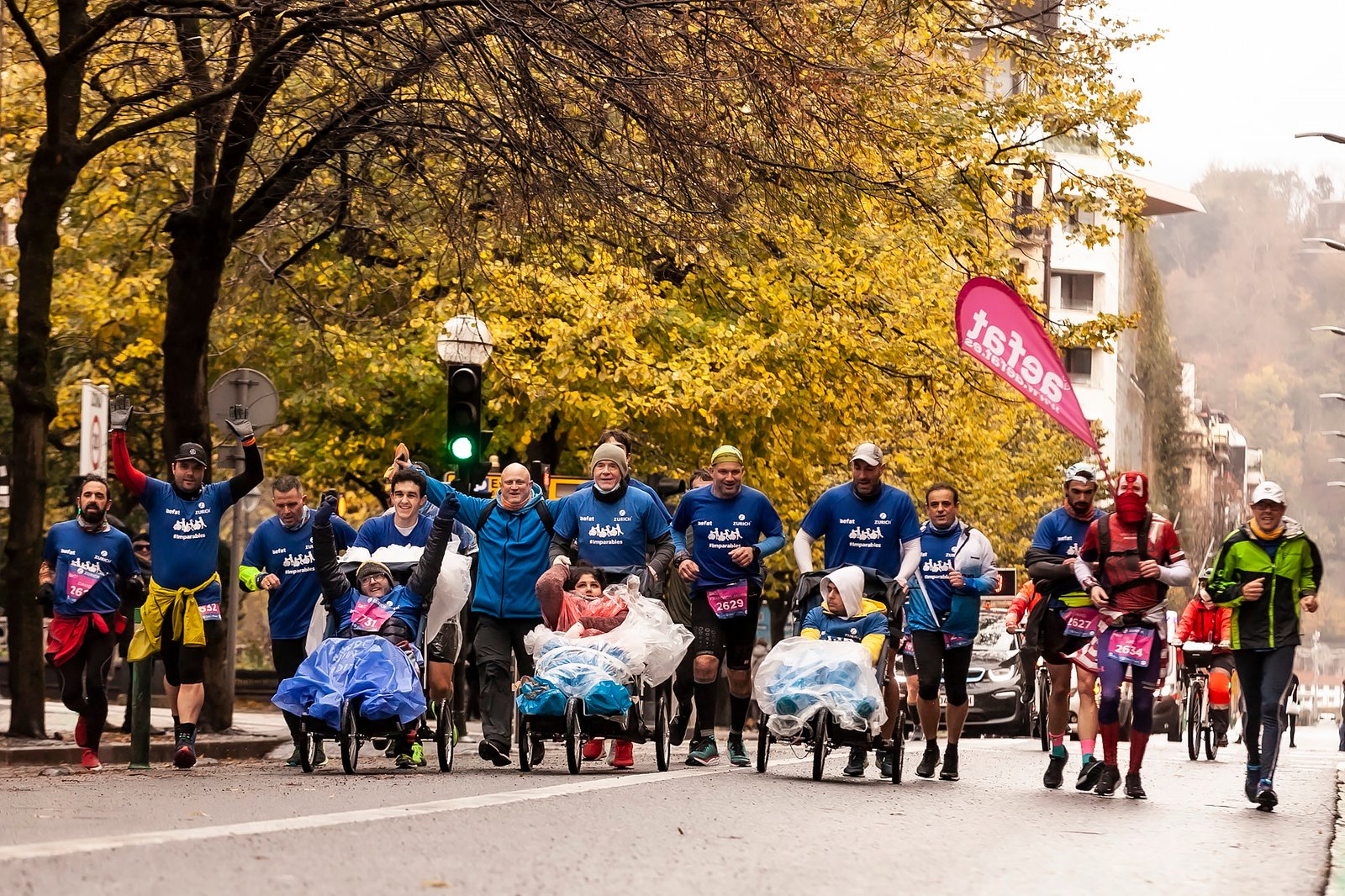Gonzalo lleva silla de chico capucha blanca Equipo Zurich Aefat en Maratón San Sebastián 2021 llegando
